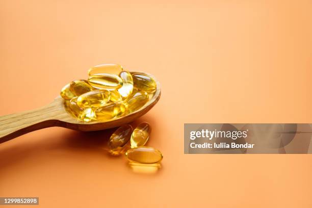 omega 3 fish oil capsules on wooden spoon. - fish liver stock pictures, royalty-free photos & images