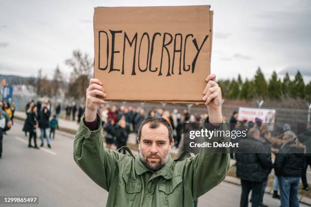 angry protestor holding a banner with text democracy on a street - man holding placard stock pictures, royalty-free photos & images