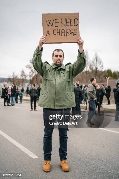 protestor on a street holding a banner with text we need a change - justice reform stock pictures, royalty-free photos & images