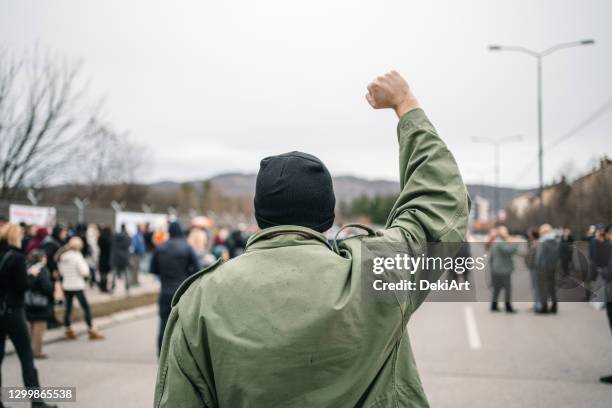 unkenntlich mann mit erhobener faust während eines protests auf einer straße - streetfight stock-fotos und bilder