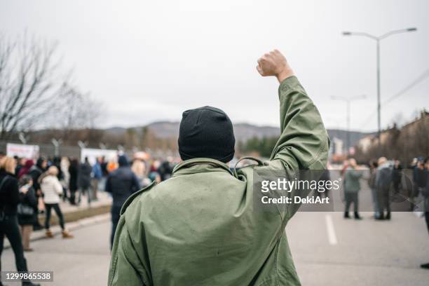 uomo irriconoscibile con pugno alzato durante una protesta in una strada - giustizia sociale foto e immagini stock