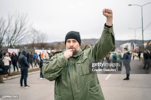 protestor with raised fist on a street blowing a whistle - fist raised stock pictures, royalty-free photos & images