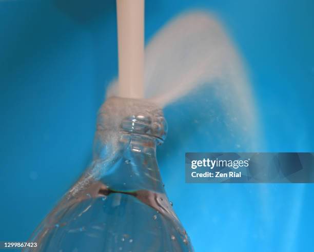 fresh water from faucet overfilling a plastic bottle against blue background - volume fluid capacity stock pictures, royalty-free photos & images