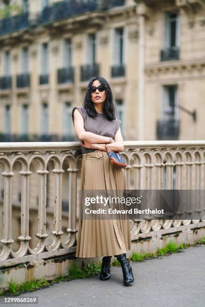 Fashion blogger Xiayan wears sunglasses from Bottega Veneta, a gray tank top from Copenhagen Muse, a beige pleated long skirt from Copenhagen Muse, a...