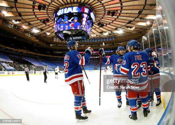 Julien Gauthier of the New York Rangers high-fives Brendan Lemieux and Adam Fox as they celebrate a goal scored by teammate Kevin Rooney during the...