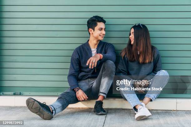 young couple sitting and looking into each other's eyes while chatting with smiling faces - girlfriend imagens e fotografias de stock