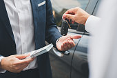 Closeup hand giving a car key and money for loan credit financial, lease and rental concept