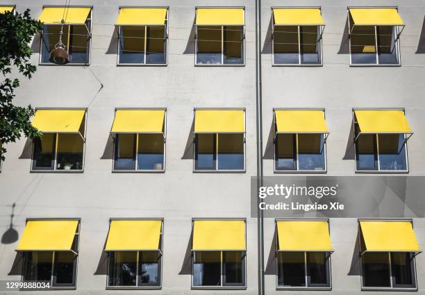 color of the year 2021 - illuminating and ultimate gray: yellow and grey building facade in copenhagen, denmark - zonnescherm gebouwonderdeel stockfoto's en -beelden