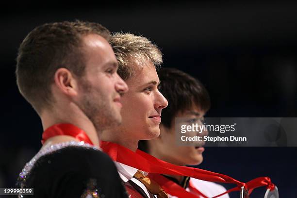 Michal Brezina of the Czech Republic , Kevin Van Der Perren of Belgium , and Takahiko Kozuka of Japan pose for photos after the men's competition...