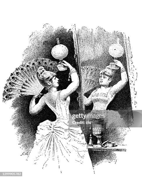 woman with peacock hand fan looks at herself in the mirror - vintage hand mirror stock illustrations