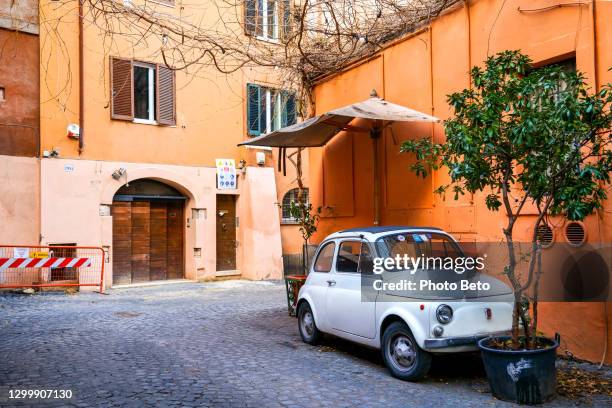 een uitstekende fiat 500 die in het oude district trastevere in het historische centrum van rome wordt geparkeerd - fiat 500 stockfoto's en -beelden