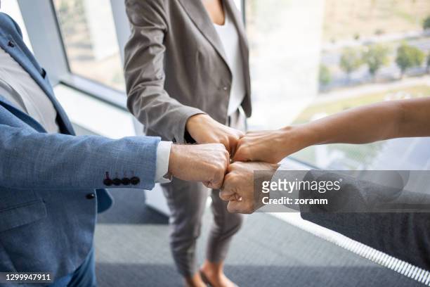 hands of four managers in fist bump together for agreement - four people stock pictures, royalty-free photos & images
