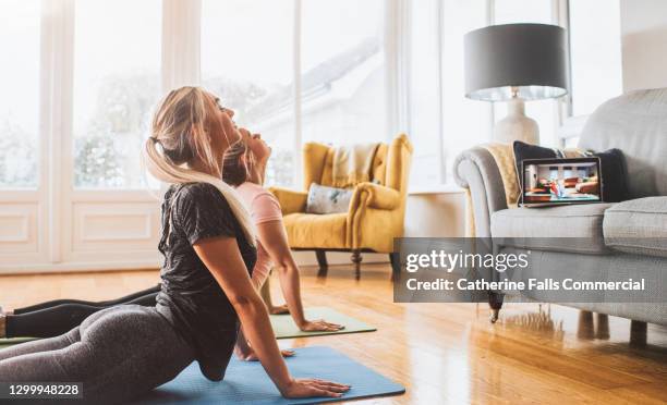 two young woman participate in an online yoga class - plano fijo fotografías e imágenes de stock