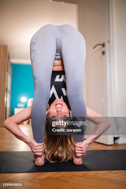 achtermening van vrouw die enkels in volledige bevindende voorwaartse kromming houdt - uttanasana - white trousers stockfoto's en -beelden