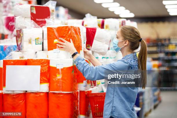 young woman reading label on toilete paper amid covid-19 outbreak - buying toilet paper stock pictures, royalty-free photos & images