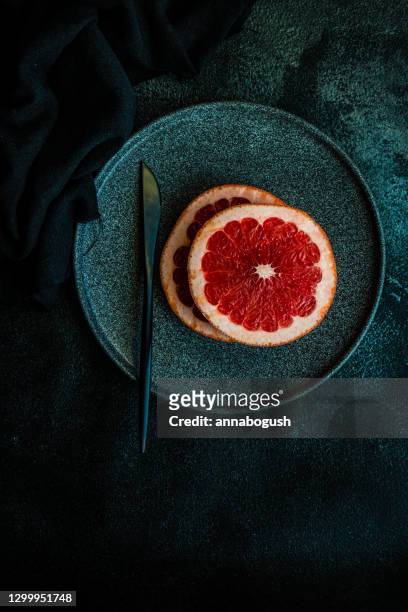 ripe pink grapefruit slices on black plate - pink grapefruit stock pictures, royalty-free photos & images