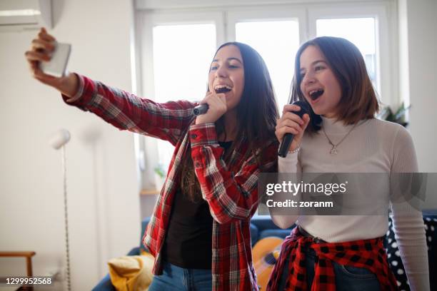 teenage girls holding wireless microphones at home and taking a selfie - duet stock pictures, royalty-free photos & images