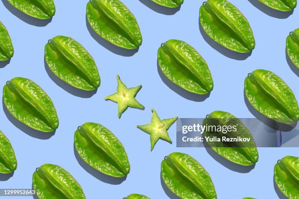repeated green carambola (star fruit) on the blue background - carambola stock pictures, royalty-free photos & images