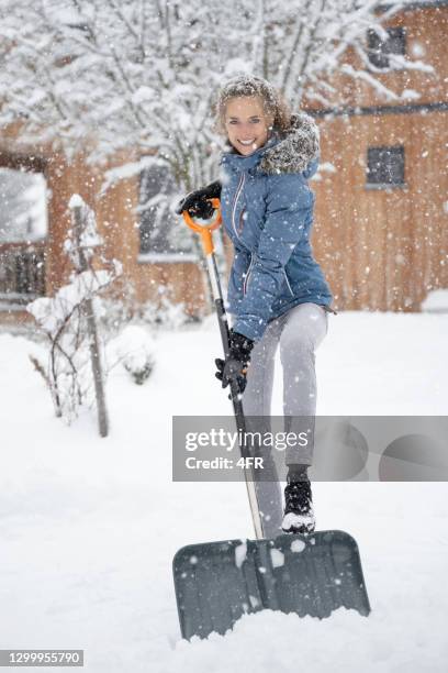 frau räumt den weg mit einer schneeschaufel in einem schweren schneesturm - snow shovel stock-fotos und bilder