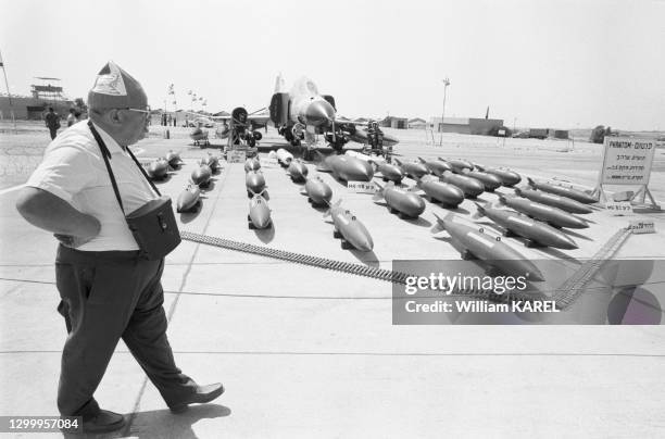 Visiteur passe devant un avion militaire et des modèles de bombes lors d'une exposition sur l'armement sur l'aéroport de Tel-Aviv le 22 juillet 1976,...