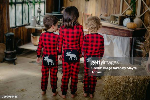 kids in matching pajamas showing their pajamas back in a cabin kitchen - reet stockfoto's en -beelden