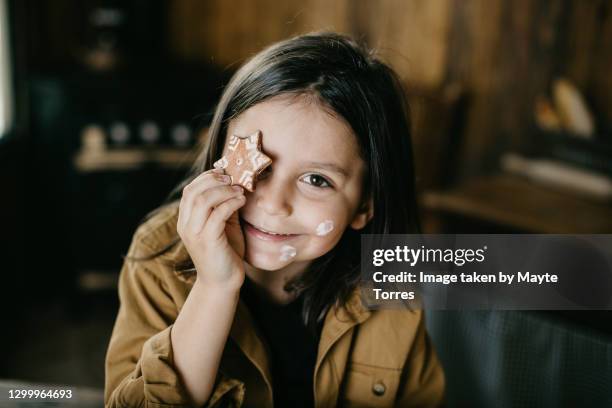 boy putting a star cookie in front of his eye with flour stains in the face - kids baking stock-fotos und bilder