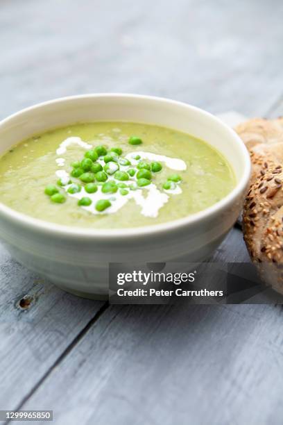 schüssel erbsen- und schinkensuppe mit sahne und brötchen auf einer rauen holzoberfläche mit kopierraum - suppenschüssel stock-fotos und bilder
