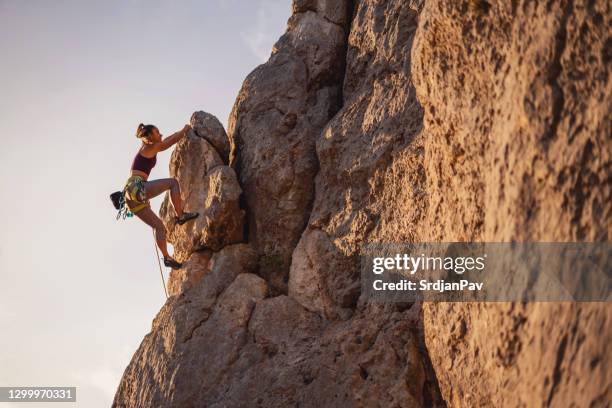 young female climber on the rock mountain - escalar rochas imagens e fotografias de stock