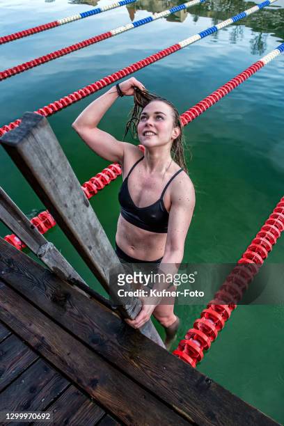 vrouw die in het ijs in burghausen zwemt - nieuwjaarsduik stockfoto's en -beelden