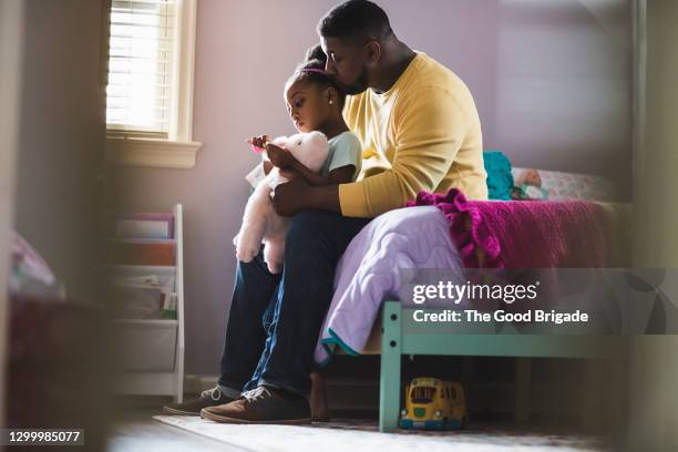 father kissing daughter on her head in bedroom at home - leanincollection dad stock pictures, royalty-free photos & images