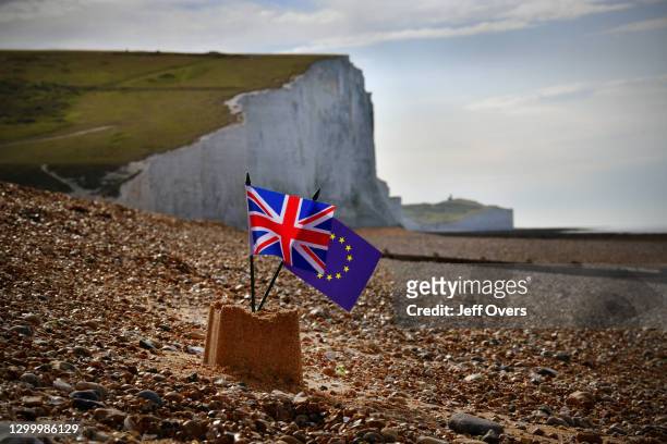 Union Jack and European Union flags sitting atop a sandcastle on Cuckmere Haven beach in East Sussex, and in the background the Seven Sisters cliffs...