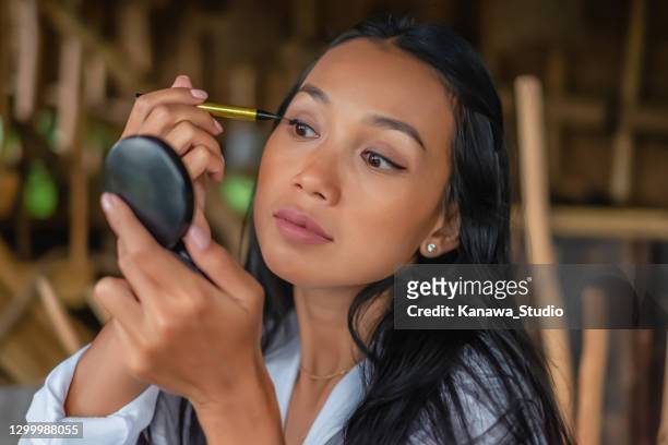 beautiful indonesian woman applying black eyeliner. - woman mascara stock pictures, royalty-free photos & images