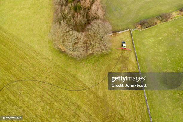 the view from a drone looking down on a tractor using a slurry injection system to spray slurry on a field - manure spreader stock pictures, royalty-free photos & images