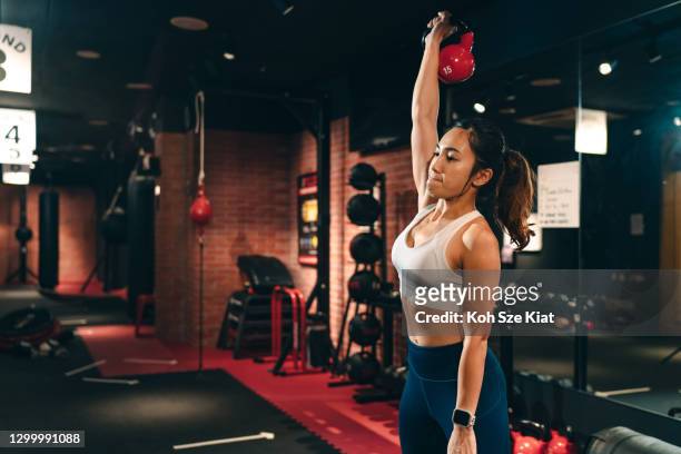 Asiática mujer haciendo entrenamiento de pesas libres en interiores