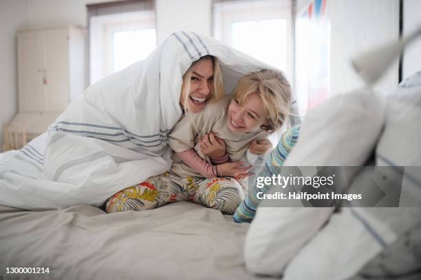 portrait of mother and small daughter indoors in bedroom, having fun. - family cover stock pictures, royalty-free photos & images
