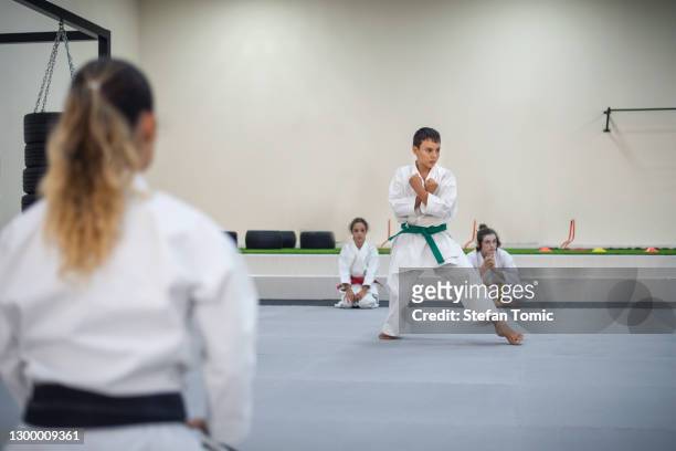 istruttore di karate nel kimono durante la visione della sessione di allenamento di karate in una palestra sportiva - cintura verde capo di abbigliamento foto e immagini stock