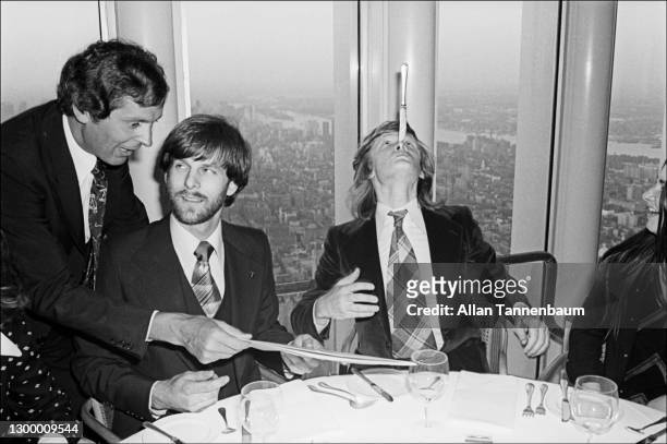 An unidentified waiter offers American climber George Willig a menu as French high-wire artist Philippe Petit balances a knife on his nose during a...