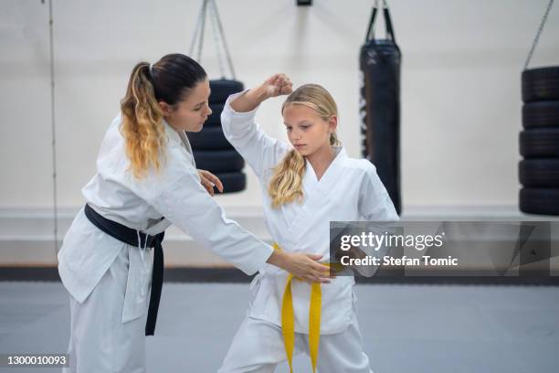 teenage girl in kimono practicing karate with a instructor in a sports gym. martial arts training session - karate stock pictures, royalty-free photos & images