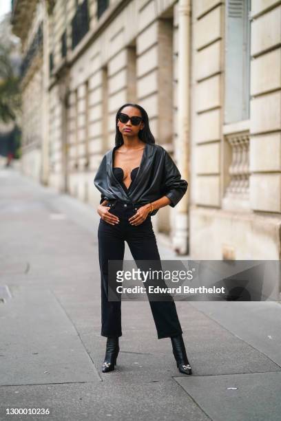 Emilie Joseph wears sunglasses from Gentle Monster, a black leather opened vintage jacket, a low-neck corset from Mango, black denim jeans pants from...