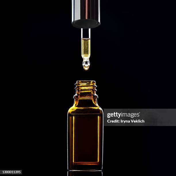 bottle of massage oil or facial serum for spa treatment on dark black background. - flacon compte gouttes photos et images de collection