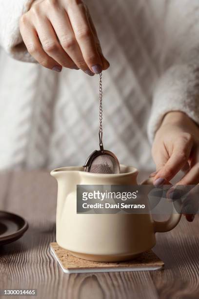 crop woman preparing tea with strainer in teapot - feierliche veranstaltung stock-fotos und bilder