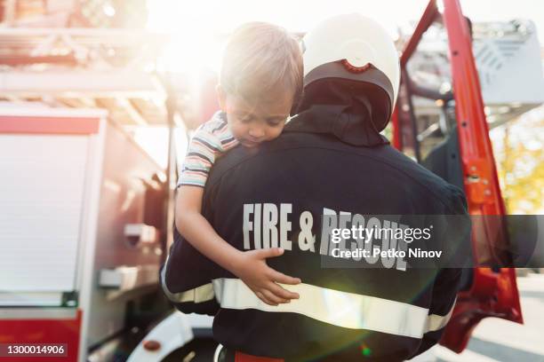 firefighter carrying stressed little boy - rescue stock pictures, royalty-free photos & images
