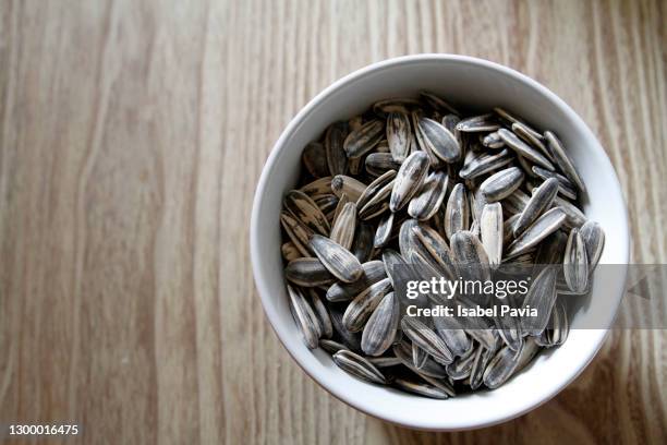 bowl of sunflower seeds on wooden table - zonnebloempit stockfoto's en -beelden