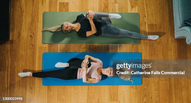 top down image of two woman on yoga mats holding their knee to their chest - hamstring stock pictures, royalty-free photos & images