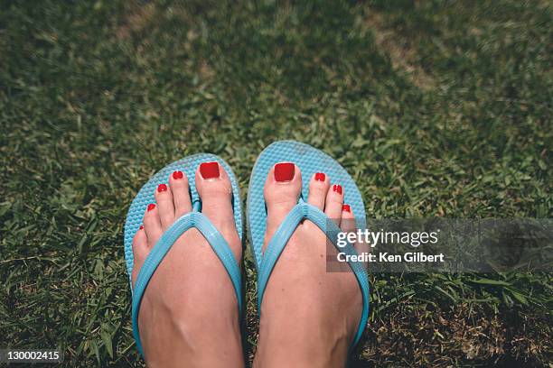 wman's pedicured feet in flipflops rest on grass - thong stock pictures, royalty-free photos & images