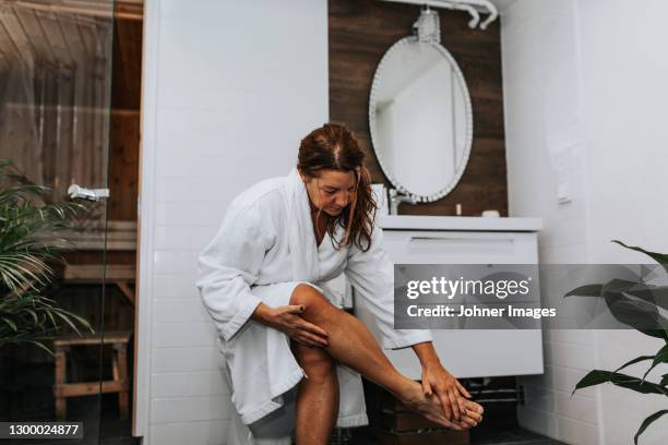 woman in bathroom applying cream - older woman legs fotografías e imágenes de stock