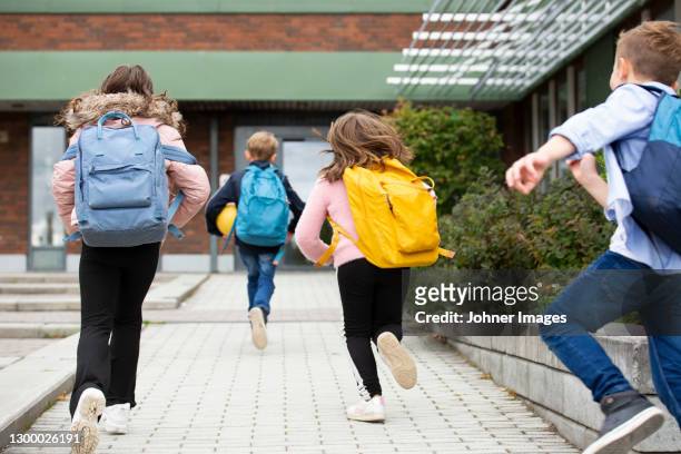 rear view of schoolchildren running - backpacks stockfoto's en -beelden