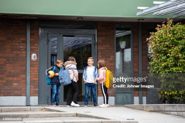 children talking in front of school building - cour récréation photos et images de collection