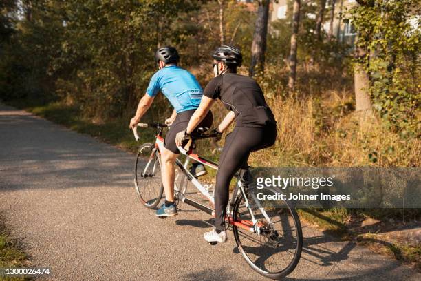 visually impaired female triathlete training on tandem bicycle with her guide and coach - ciclismo tandem fotografías e imágenes de stock