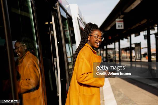 smiling woman leaving bus at bus station - dark skin stock pictures, royalty-free photos & images